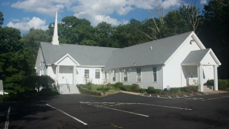 White church building beside a parking lot