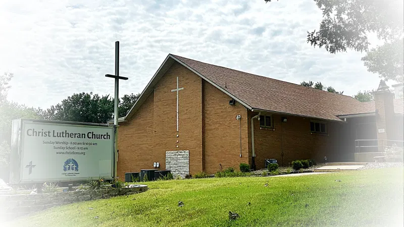 Brick church exterior with a lawn and roadside sign